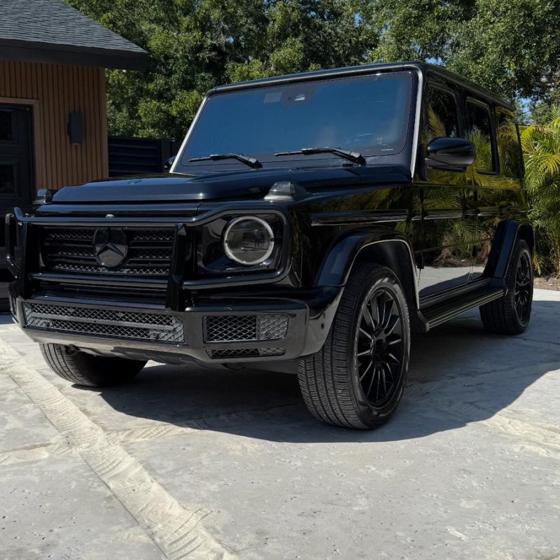 Sleek black luxury sports car parked in front of a modern building, showcasing TWM Exotics Tampa’s premium rental fleet